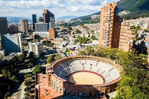 A large circular stadium surrounded by urban buildings and a mountainous backdrop.