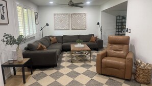 A living room with a sectional sofa, a leather armchair, a coffee table, and a decorative vase with plants. - Old Town Scottsdale Pool Oasis - Walk to Everything! (Scottsdale)