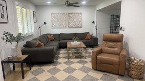A living room with a sectional sofa, a leather armchair, a coffee table, and a decorative vase with plants. - Old Town Scottsdale Pool Oasis - Walk to Everything! (Scottsdale)