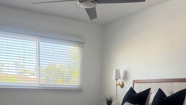 A bedroom with a bed, a ceiling fan, a nightstand with a lamp, and a window with blinds. - Old Town Scottsdale Pool Oasis - Walk to Everything! (Scottsdale)
