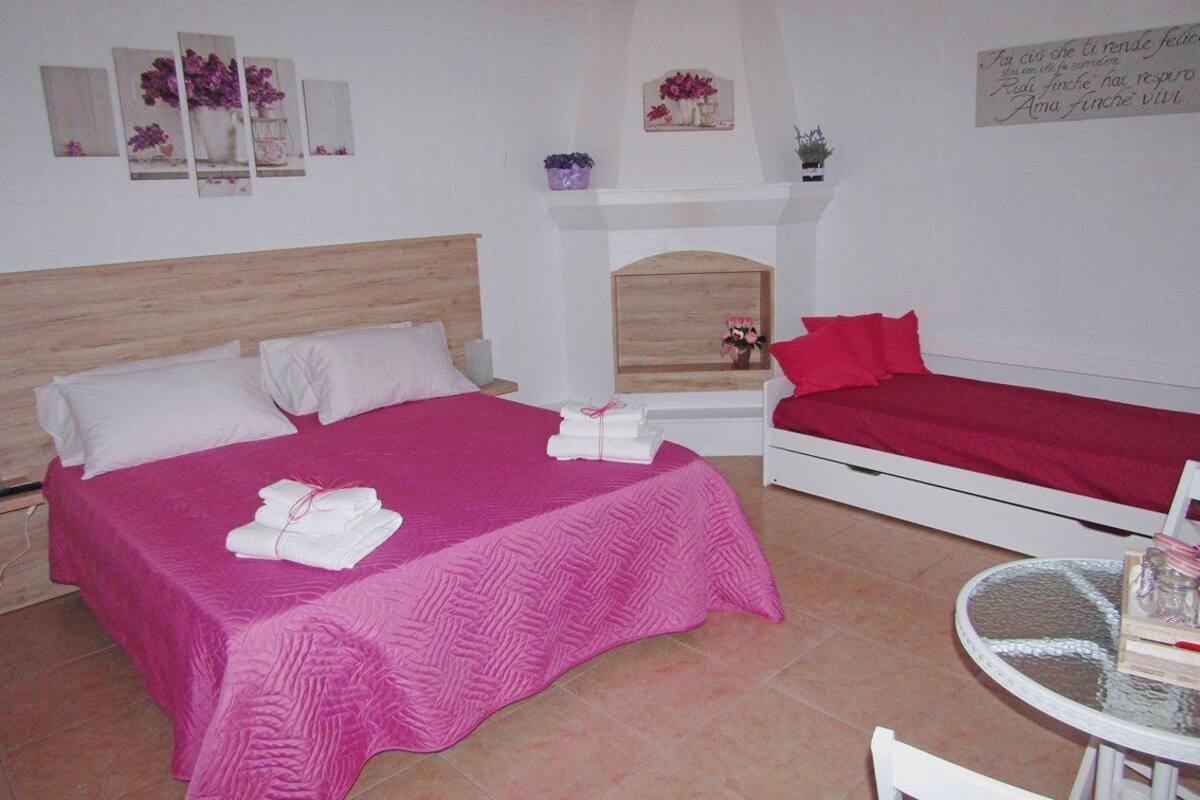 A bedroom with two beds, a fireplace, and a small table.