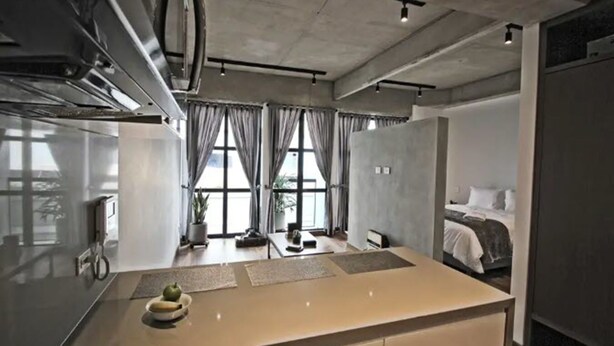 A modern hotel room with a kitchenette, a bed, and large windows. - Virrey Condos By Velvet Luxury (Bogotá)
