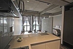 A modern hotel room with a kitchenette, a bed, and large windows. - Virrey Condos By Velvet Luxury (Bogotá)