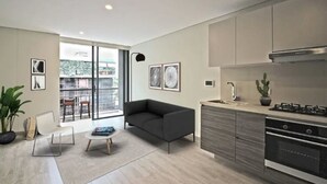 A modern kitchen with a built-in oven and a dining area with a sofa and a coffee table. - Virrey Condos By Velvet Luxury (Bogotá)