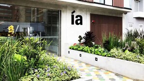 A modern building with a large glass window and a sign with the letter 'í' on the facade. - Virrey Condos By Velvet Luxury (Bogotá)
