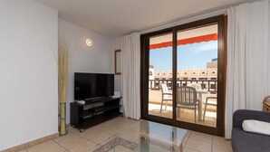 A living room with a flat-screen TV, a glass coffee table, and a sofa. - Parque Santiago I 242 - One Bed (Playa de la Américas)