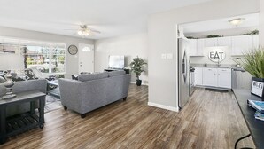 Un soggiorno moderno con un divano grigio, pavimento in legno e ventilatore a soffitto.