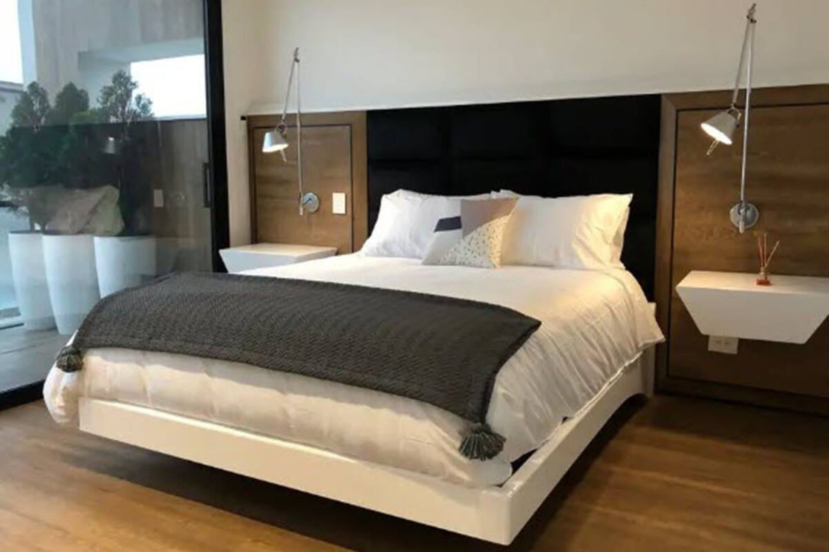 A modern bedroom with a large bed, bedside tables, and pendant lights.