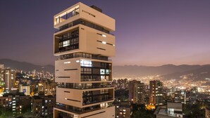 Un immeuble à plusieurs étages, doté de balcons et de grandes fenêtres, se dressant sur fond de paysage urbain nocturne.
