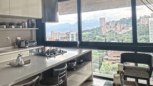 Une cuisine moderne avec une grande fenêtre, une cuisinière à gaz et une chaise.