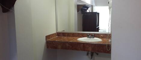 Un baño con encimera de mármol, lavamanos y espejo.