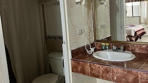 Un baño con inodoro, lavamanos y cortina de ducha.