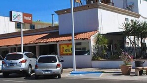 Un edificio con un letrero que dice 'Hotel Posada del Vino' y un anuncio de Coca-Cola. Hay dos coches estacionados en la entrada.