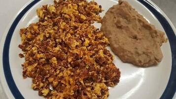 Un plato con huevos revueltos y una porción de pan plano.