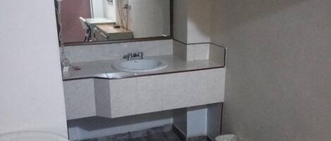 A bathroom with a white sink, a mirror, and a trash bin.