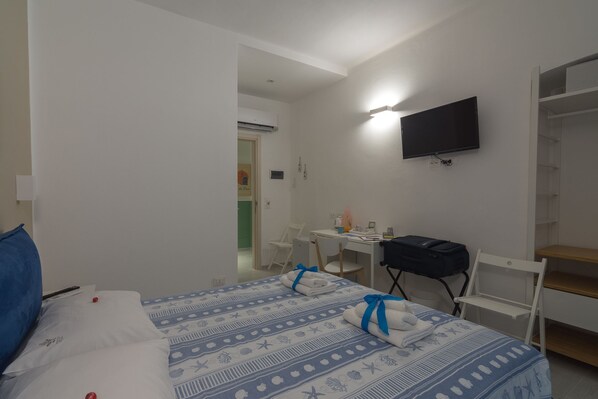 Una habitación de hotel con una cama, un escritorio, una silla, un televisor y un armario.
