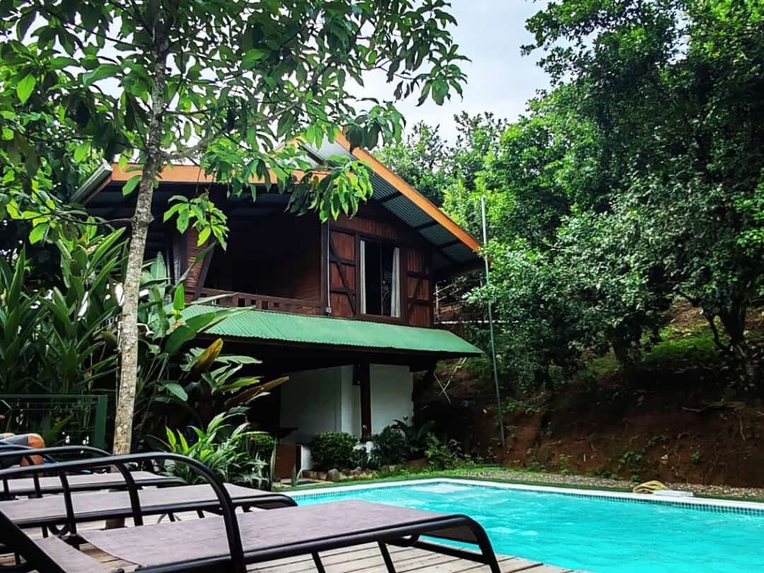 A poolside area with a wooden deck and lounge chairs.