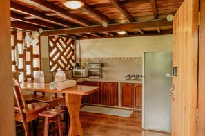 A kitchen with wooden cabinets, a refrigerator, a microwave, and a dining table with chairs.
