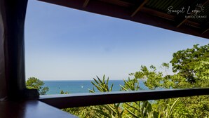 Vista des d'una finestra sobre una platja amb vegetació i un cel serè.
