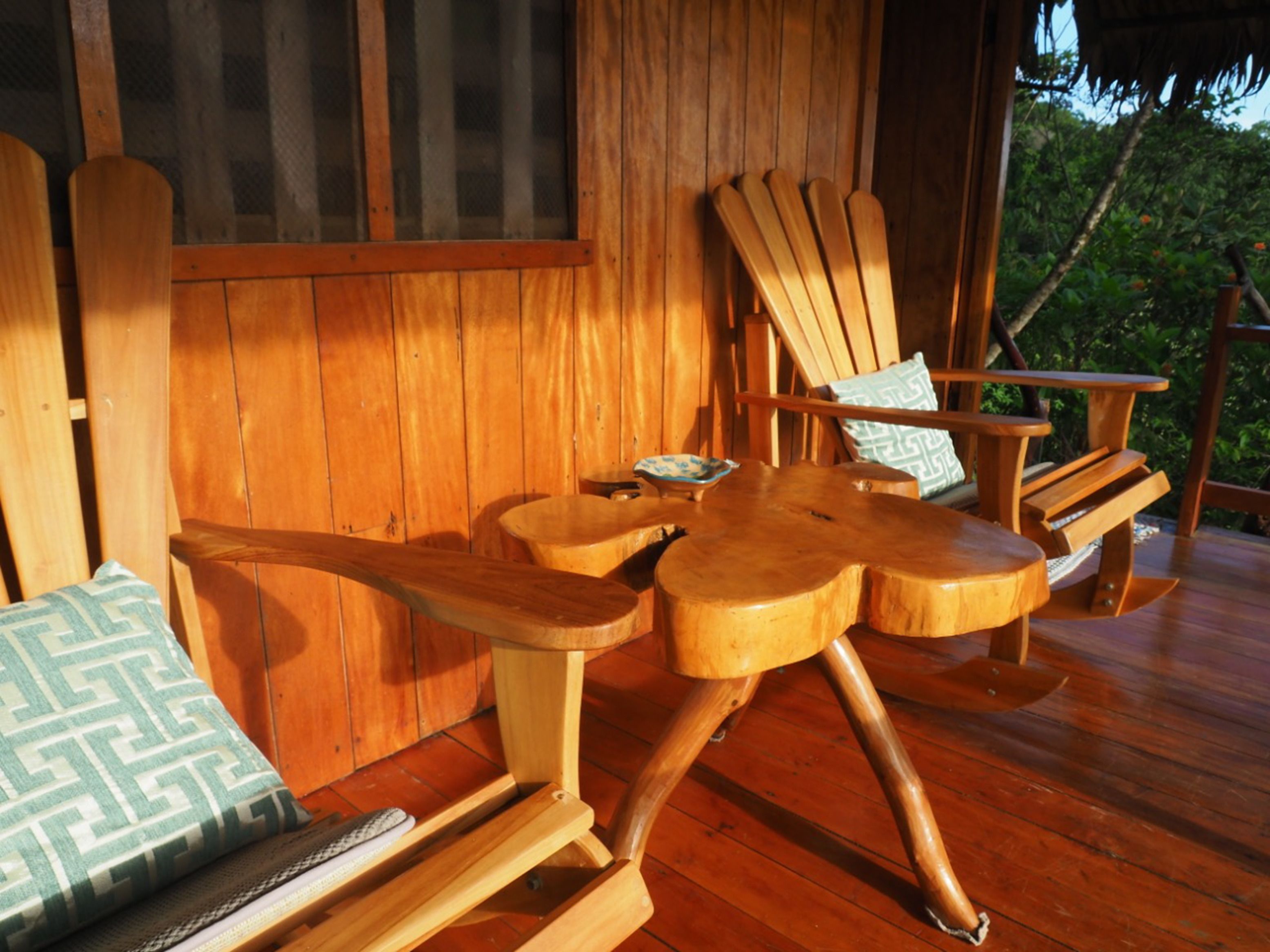 A wooden deck with a wooden table and two wooden chairs.