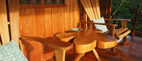 A wooden deck with a wooden table and two wooden chairs.