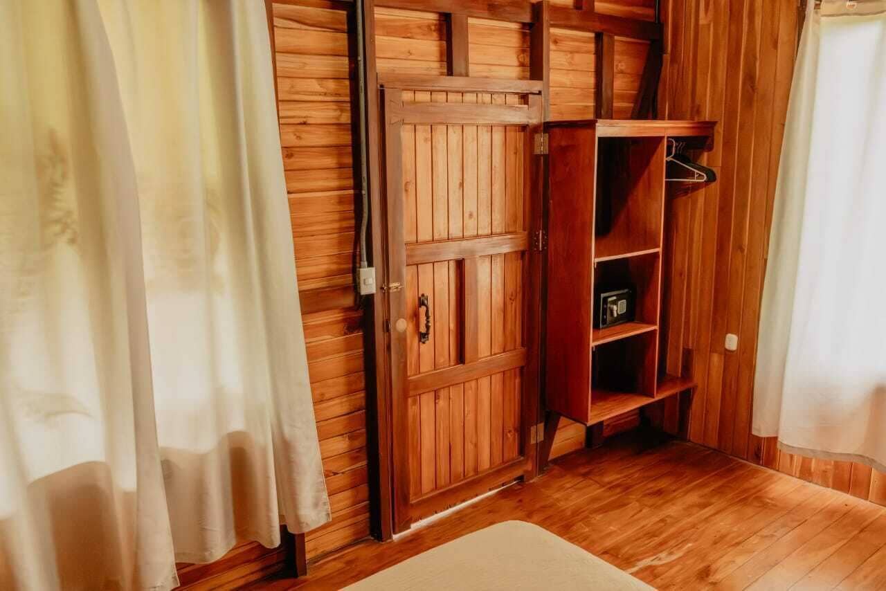 Una habitación de madera con un armario, un estante con ropa y una alfombra blanca.