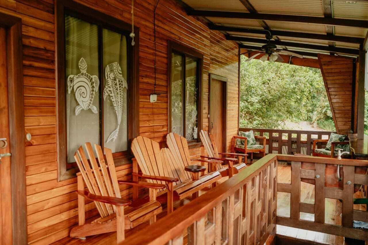 Una cabaña de madera con un porche amoblado con sillas Adirondack y una pequeña mesa.