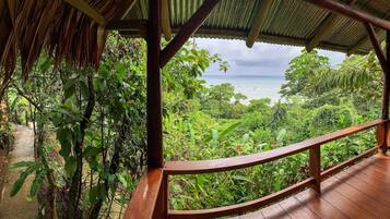 A wooden deck with a view of a lush green landscape and a beach in the distance.