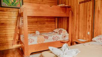 A wooden cabin room with a bunk bed, a single bed, and a wooden ladder.
