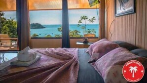 Habitació amb un llit, vista al mar i un logotip a la paret.