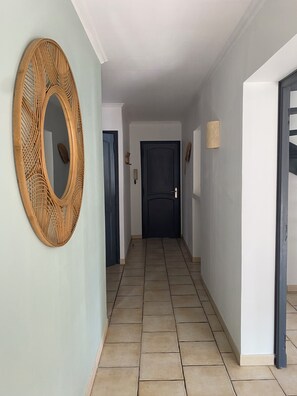 Un couloir avec un grand miroir en bois, une porte sombre et un mur de couleur claire.