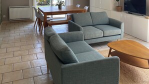 A living room with a sofa, coffee table, TV, and a dining area with a table and chairs.