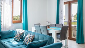 A modern living room with a blue sofa, a dining table, and teal curtains. - Kaylie Apartment, 3 bedroom place in Pula, Croatia (Pula)