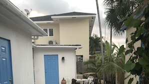 A courtyard with a gravel path, potted plants, and a blue door. - Beach Hideaway (Nassau)