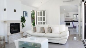 Una sala de estar moderna con un sofá blanco, una mesa de centro de vidrio y una chimenea.