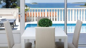 Un balcón con piscina, muebles blancos y vista al mar.