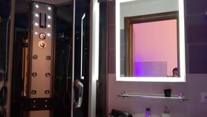 A modern bathroom with a glass shower enclosure, a vanity with a pink sink, and a mirror with illuminated edges. - Modina Guest House (Rome)