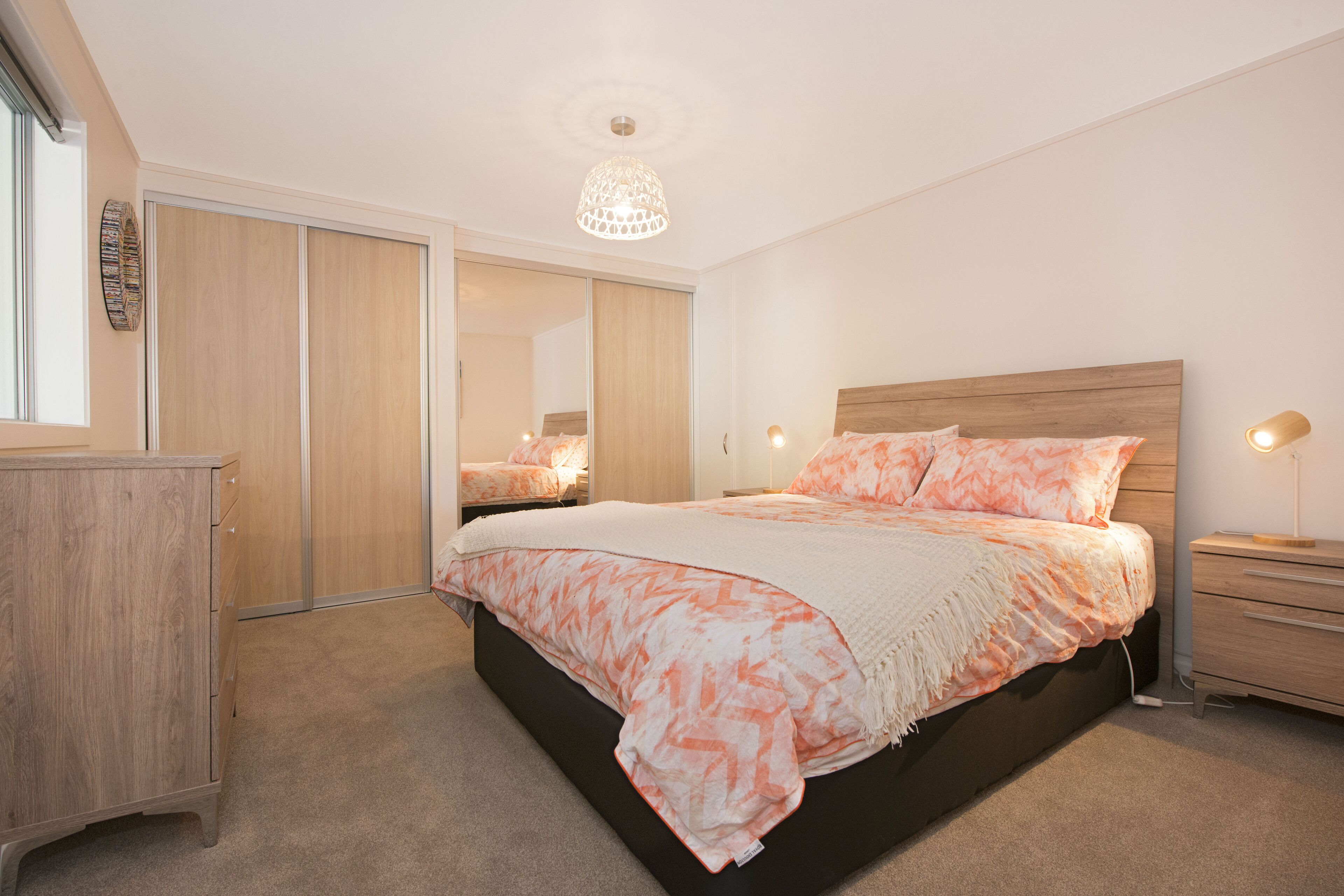 A bedroom with a bed, a wardrobe, a bedside table, and a lamp.