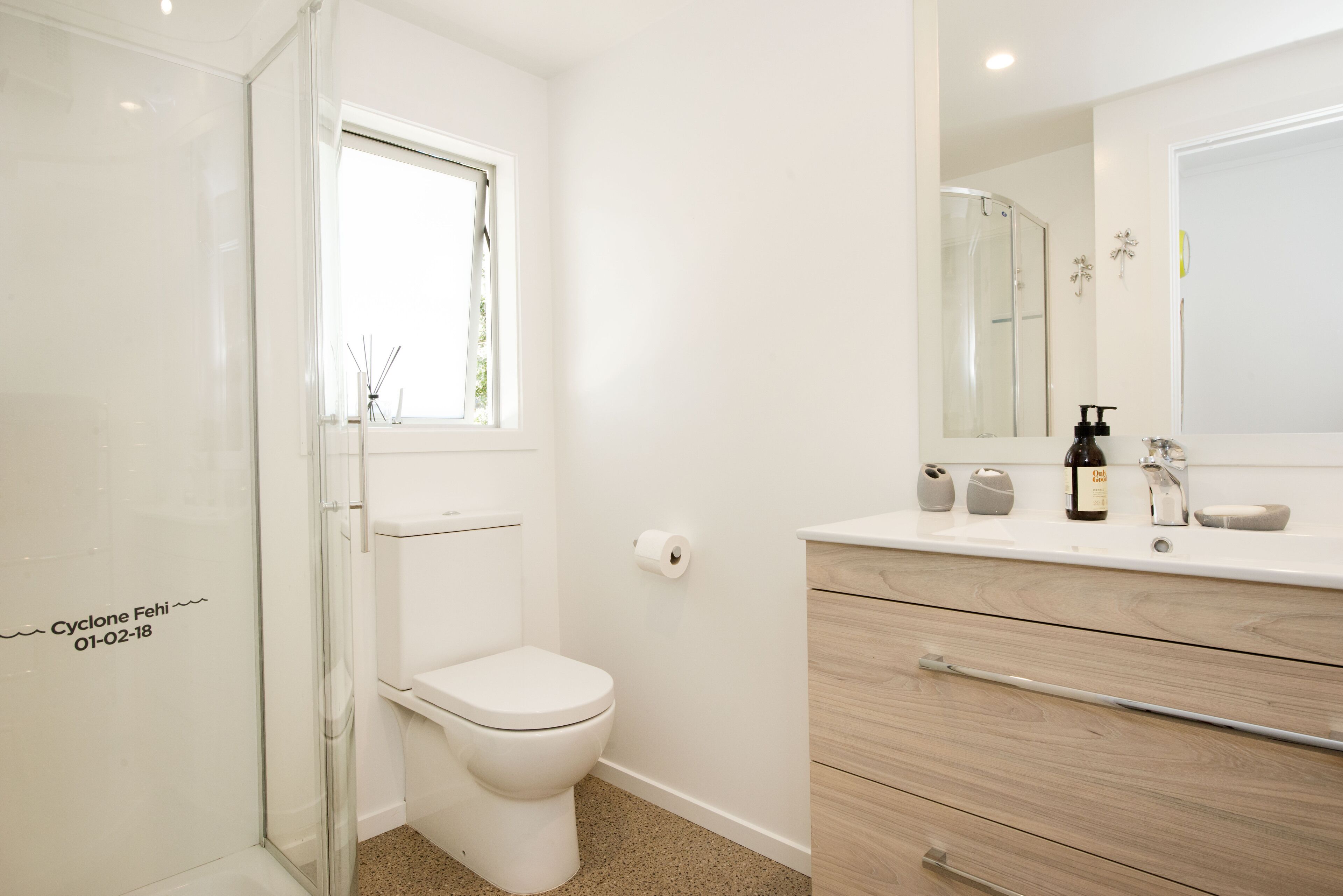 Un baño moderno con ducha acristalada, inodoro, tocador con espejo y lavabo.