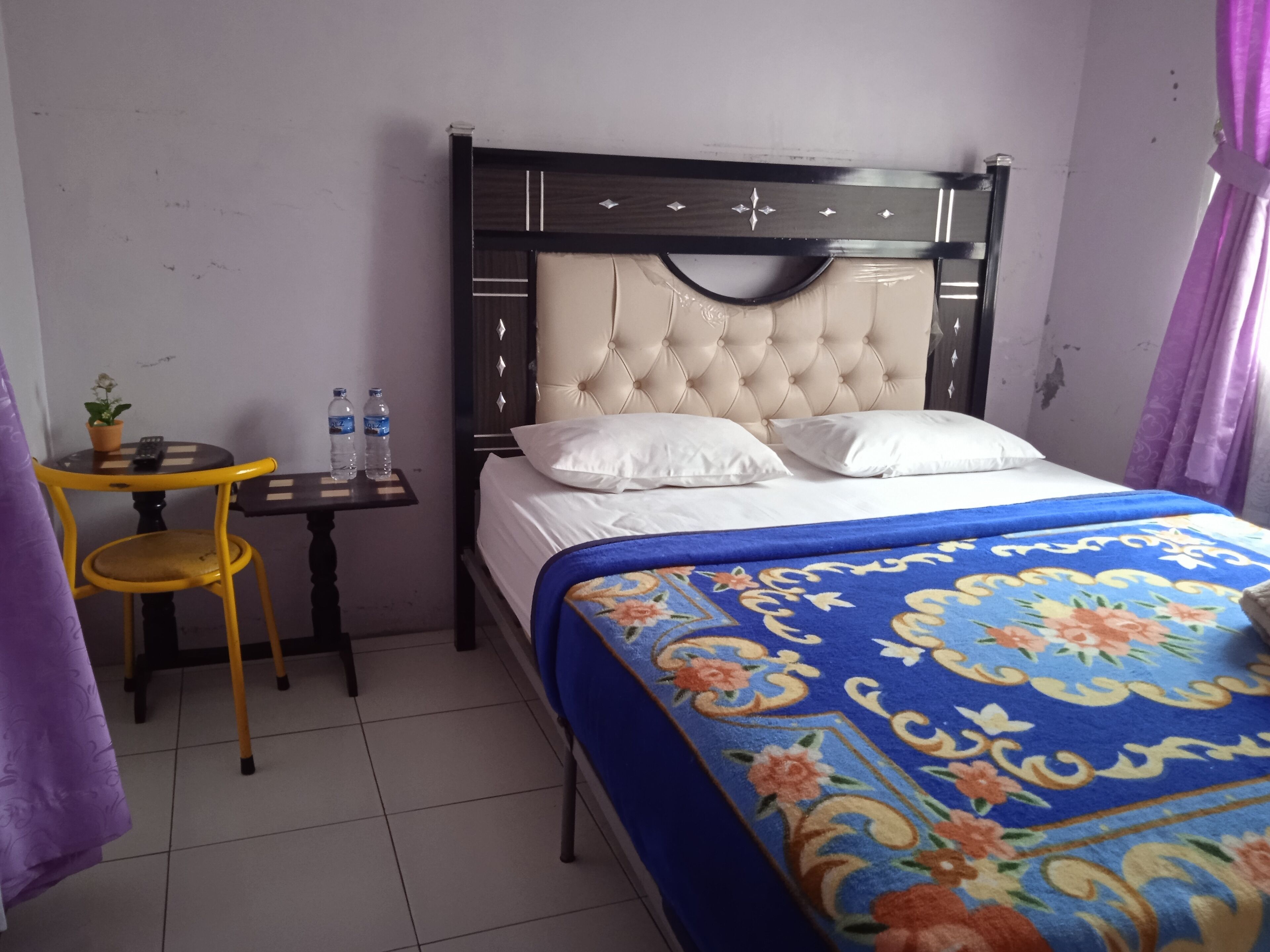 A bedroom with a bed, a nightstand, a chair, and a small table.