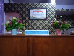 A reception desk with a sign reading "RECEPTIONIST" and a framed certificate on the wall behind it. - Trivadoh Syariah Hotel (Padang Panjang)
