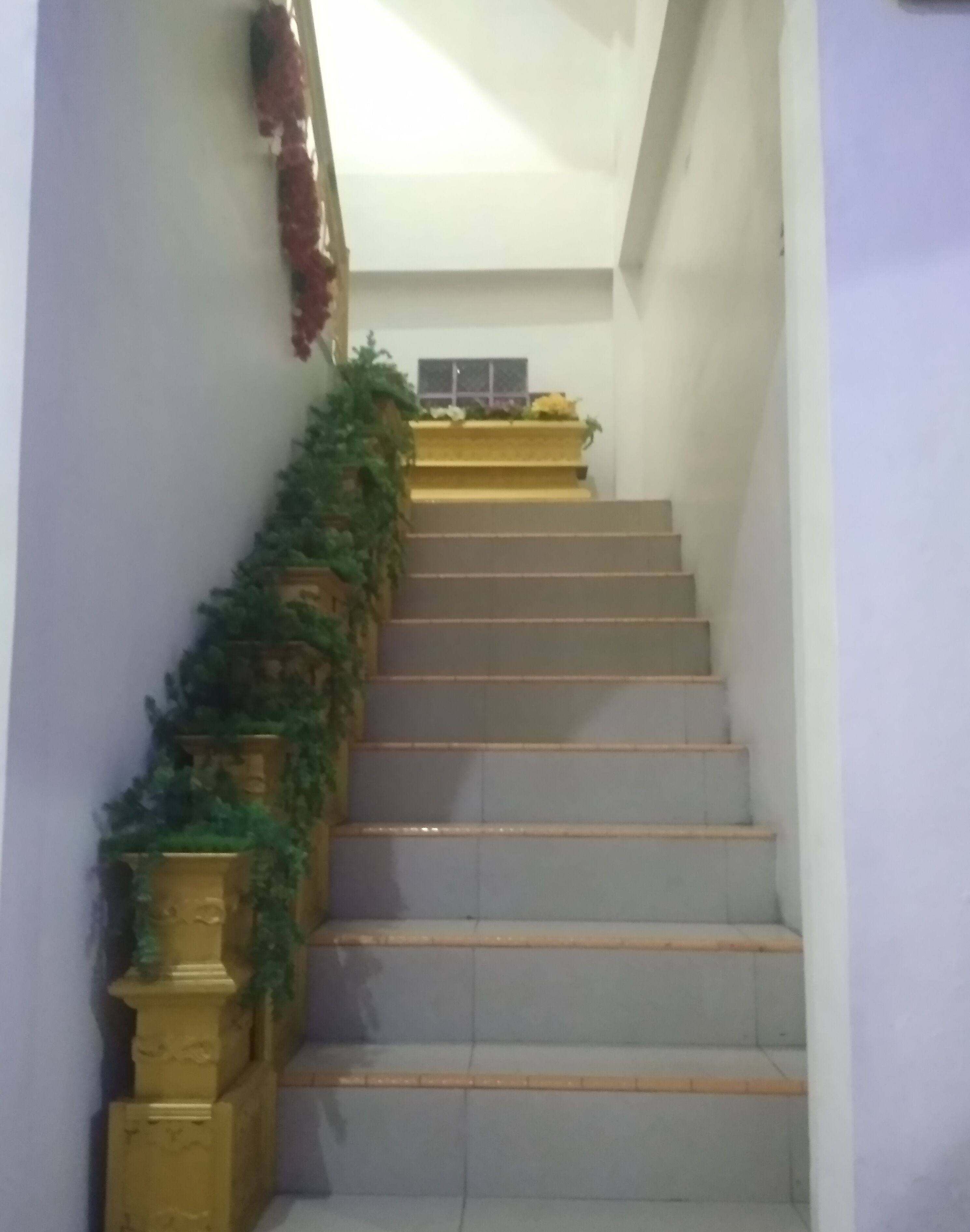 A staircase with a floral decoration on the wall and a small window at the top.