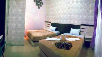 A hotel room with two beds, a small table with a red object, and patterned wallpaper.