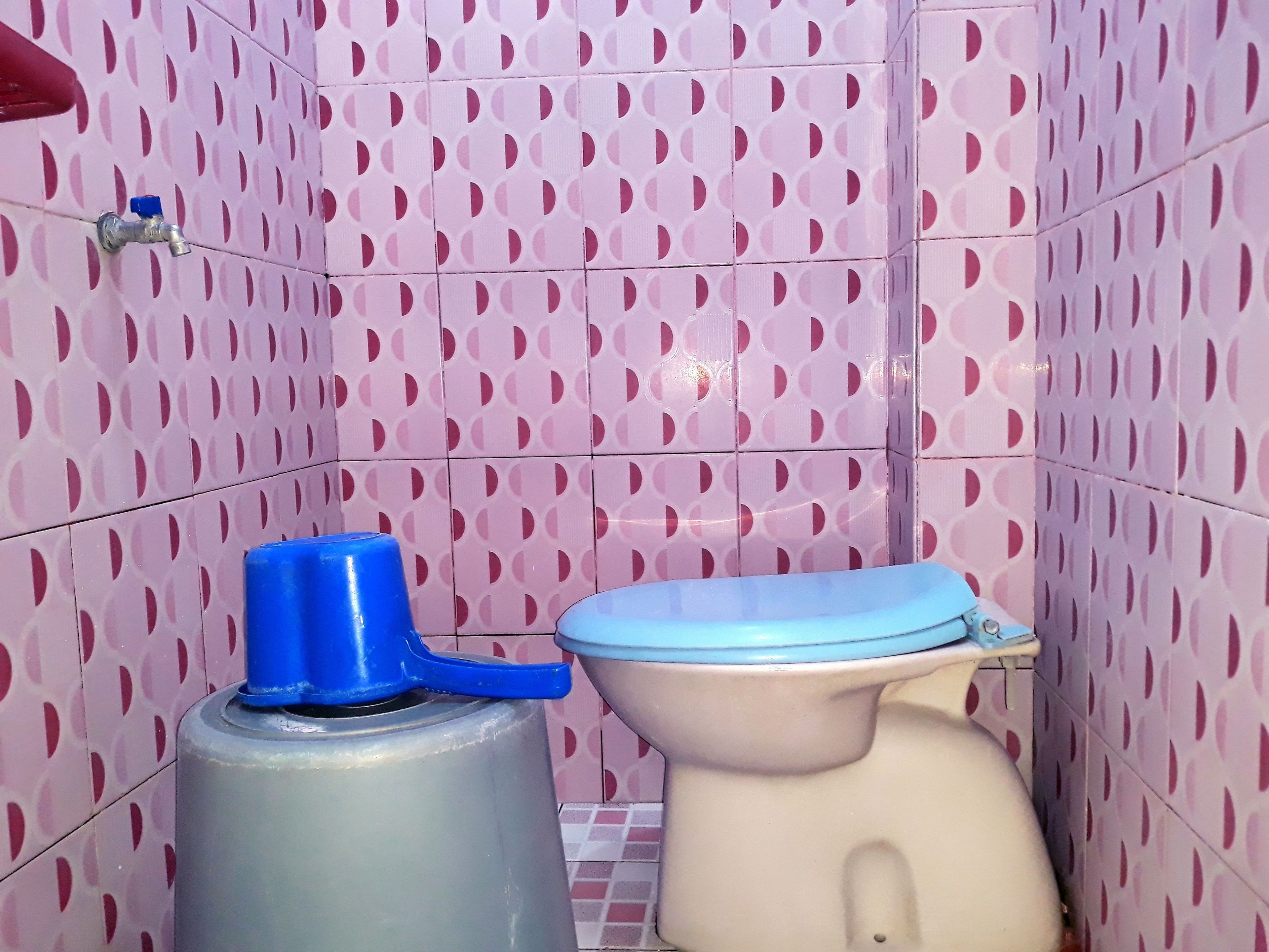 A bathroom with pink patterned tiles, a toilet, and a water dispenser.