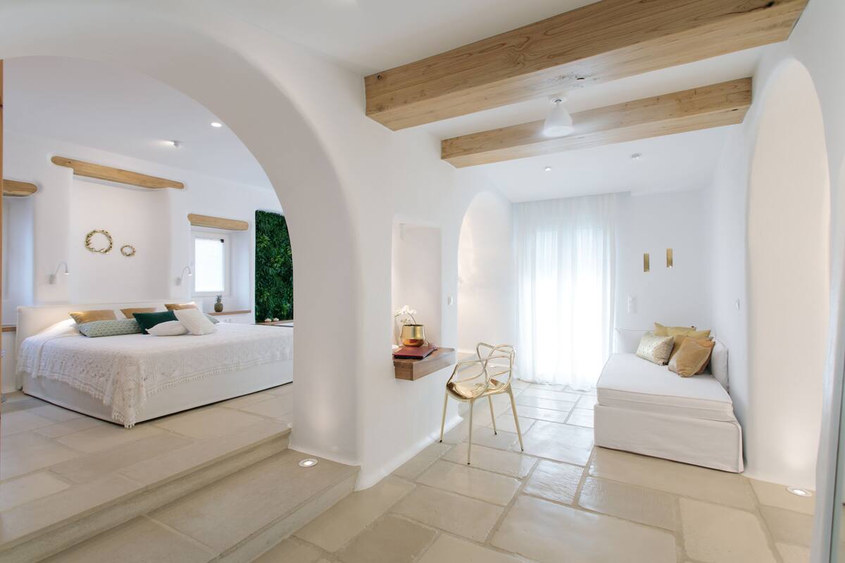 A spacious room with a large bed, a seating area with a sofa, and a small table with a lamp.