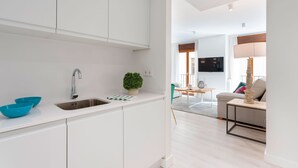 Une cuisine moderne avec des armoires blanches, un évier en acier inoxydable et des bols bleus. On peut voir une petite plante en pot sur le comptoir.