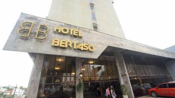 A hotel entrance with a large glass facade, a prominent 'BB HOTEL BERTASO' sign, and a red car parked in front.