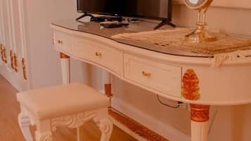 A white vanity with a television, a small stool, and a mirror.