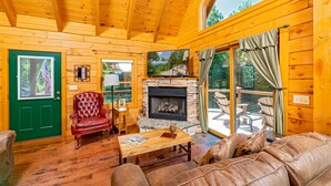Un intérieur de chalet chaleureux avec une cheminée, des meubles en cuir et un manteau de cheminée en pierre.