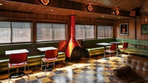 A diner with checkered flooring, red and green booths, and a central red stove. - The Dive Motel & Swim Club (Nashville)